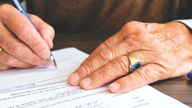 Persona mayor firmando un documento legal durante la tramitación de una herencia