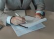 Persona revisando y firmando un contrato de trabajo en una mesa de oficina